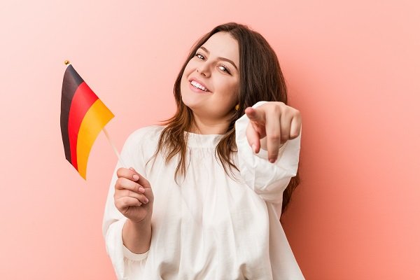 Girl holding German flag pointing out how to study in Germany for free