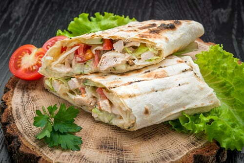 Tortilla wraps with grilled chicken or vegetarian tarteel of fresh vegetables on a wooden background.