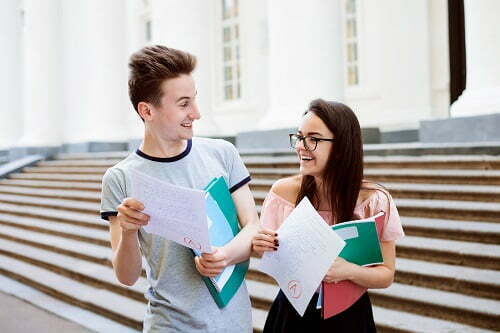 Two happy students have received excellent result of final test, look at each other and can`t believe their eyes that they have got the highest A grade
